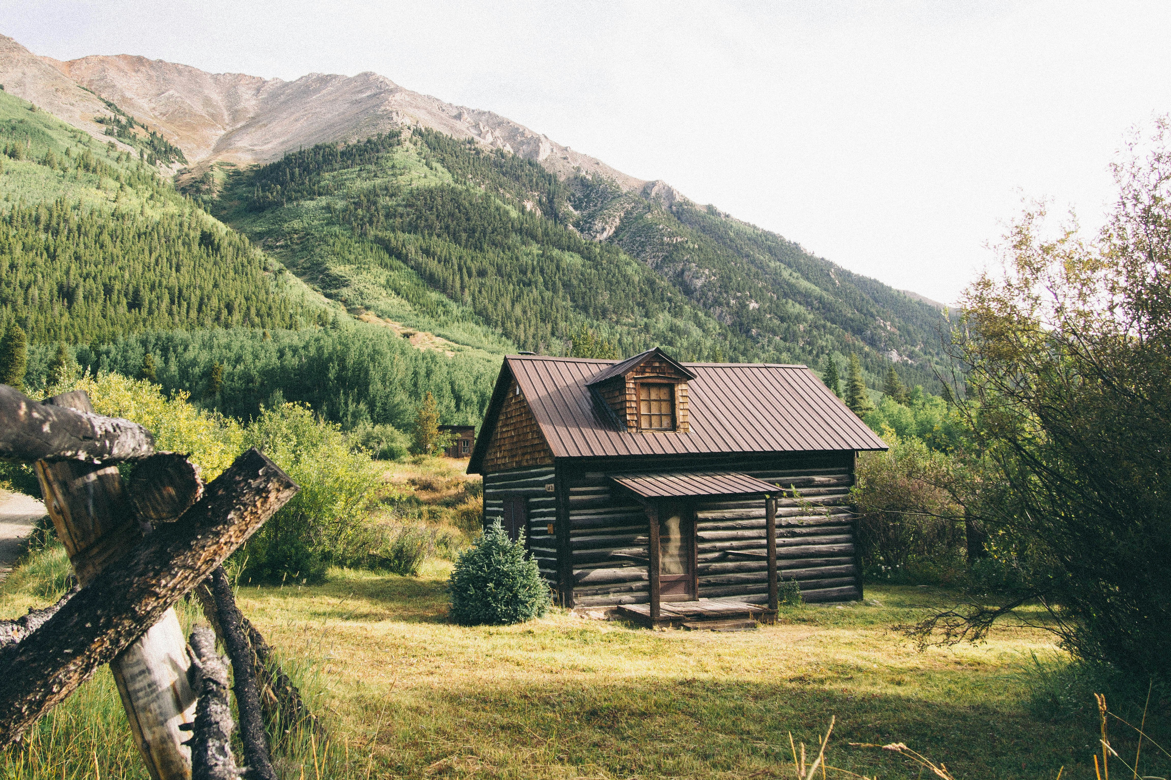 brown wooden house near mountains at daytime